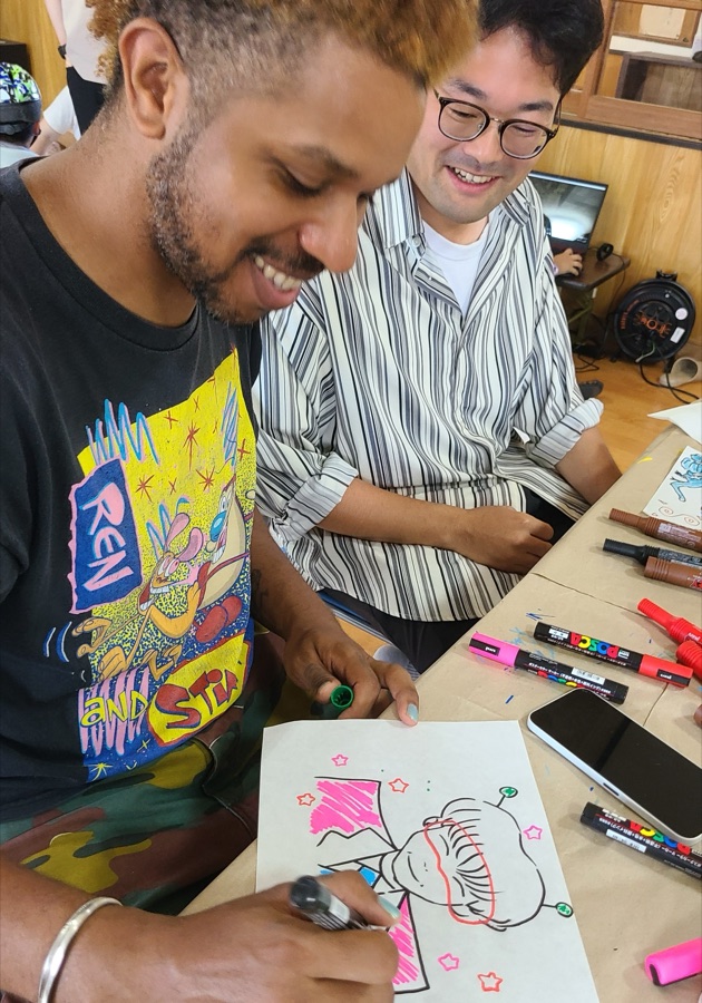 William en train de créer aux côtés d'un artiste, à Itoshima au Japon
