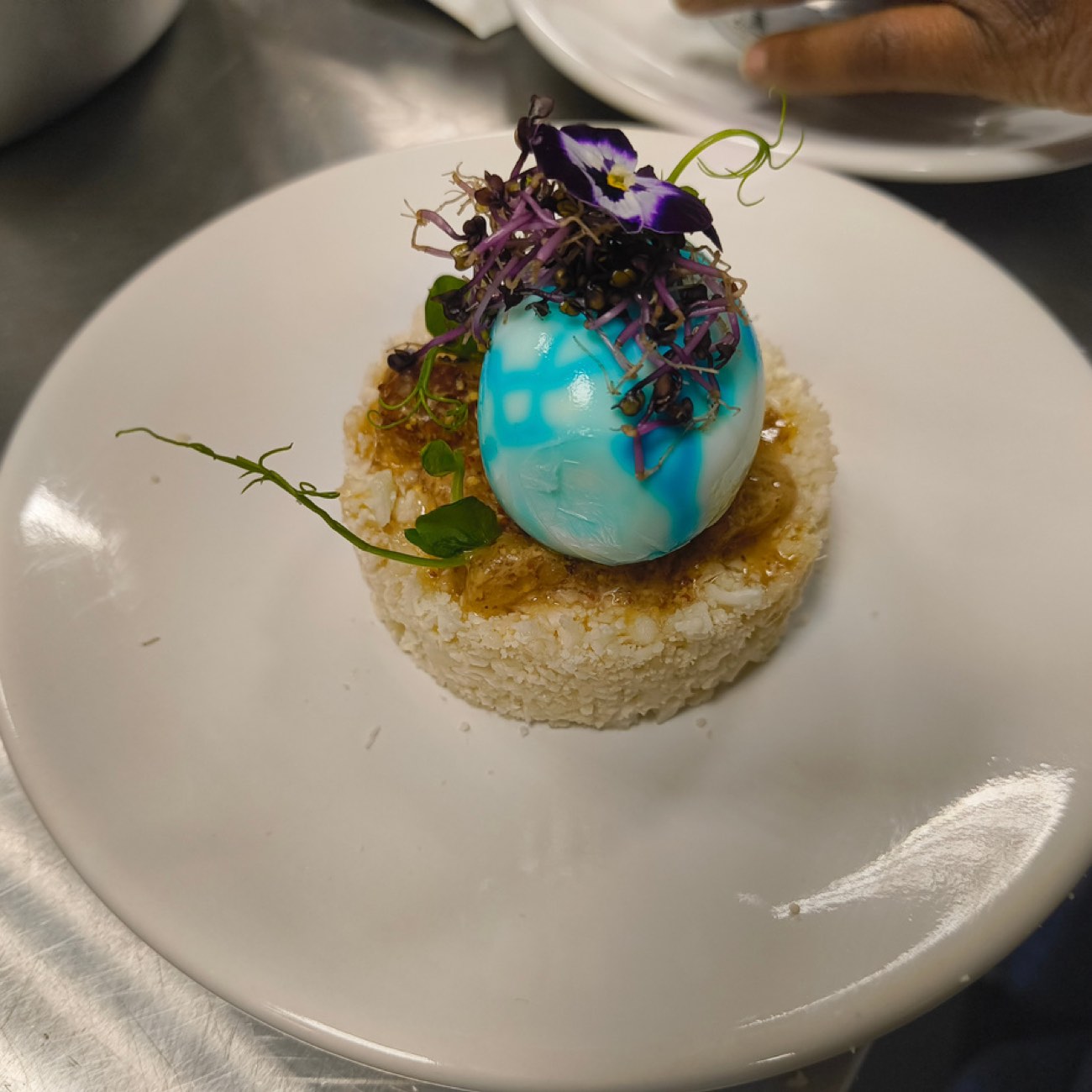 Œuf marbré turquoise sur galette de riz, fleur de pensée et pousses